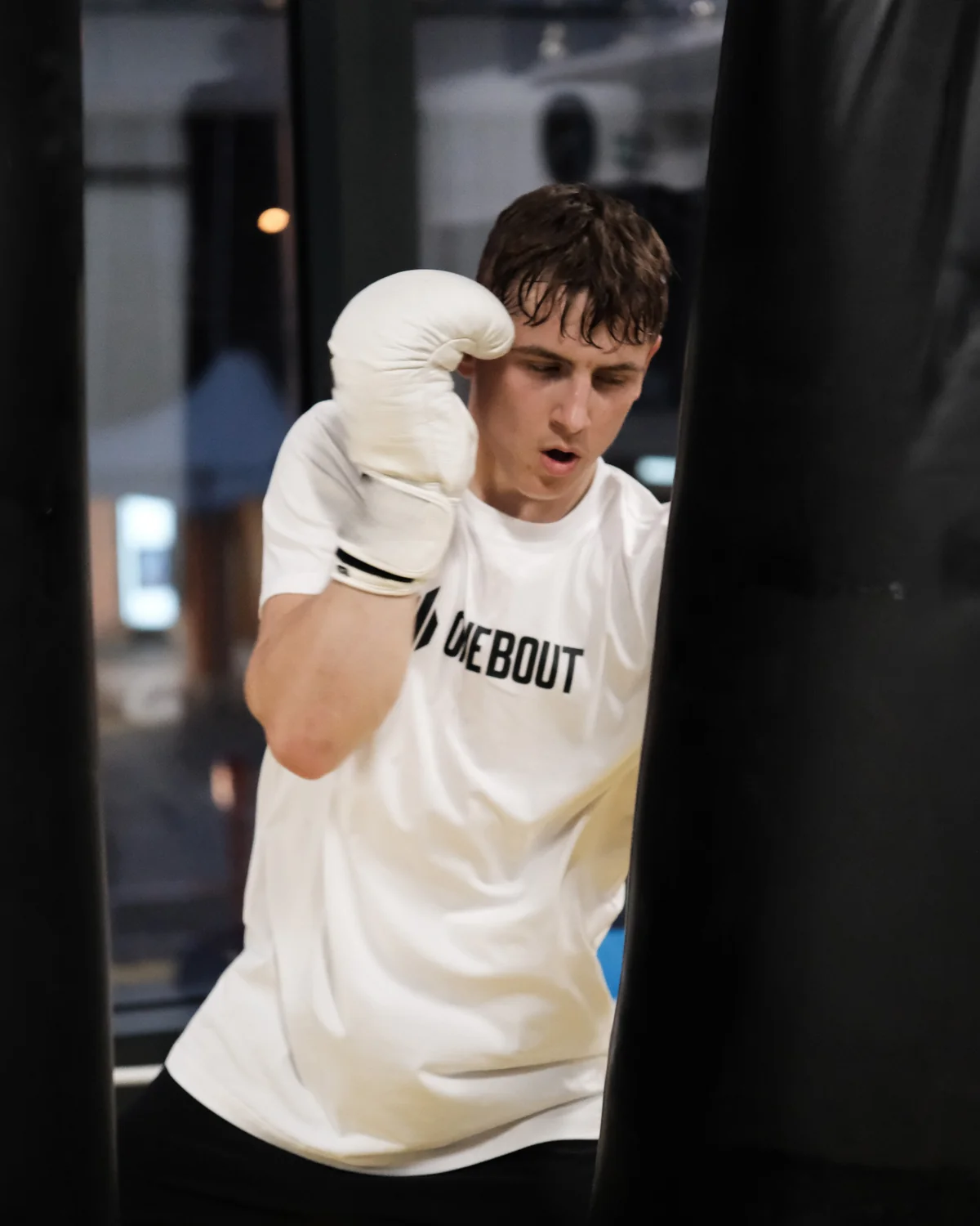 Filip Cingroš, MMA fighter, punching a bag in a white One Bout tee